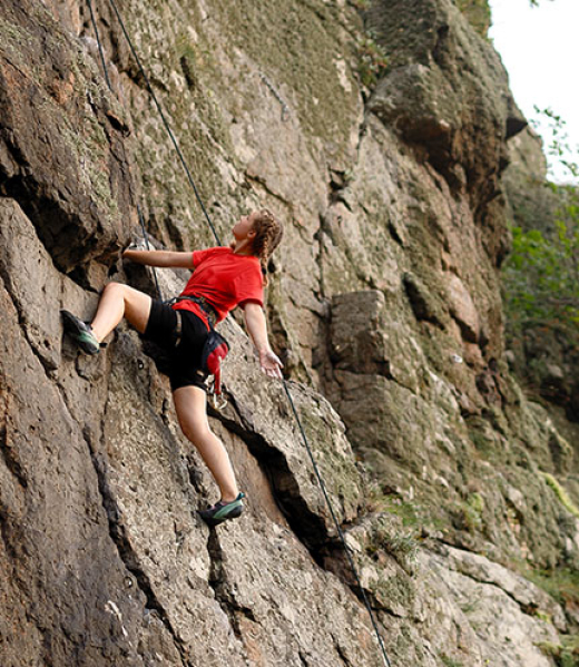 Climber overcomes challenging climbing route. A girl climbs a rock. Woman engaged in extreme sport. Extreme hobby.